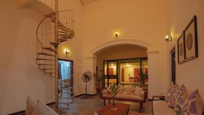 A spacious living room with a wooden staircase, a sofa set, and a dining area visible through an archway. - Idda Bouqtiue Villa  (Ahangama)
