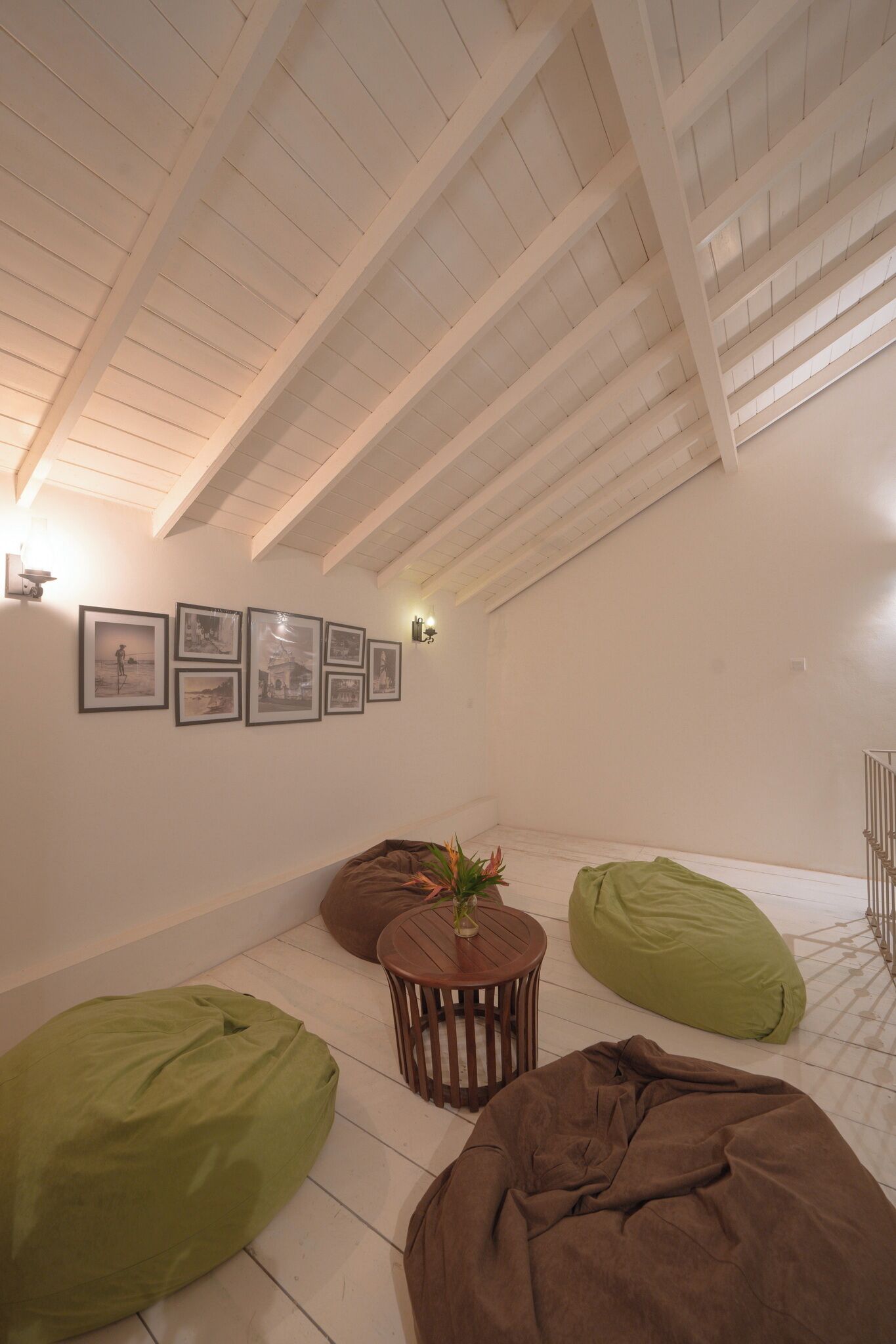 A room with a sloped ceiling, a series of framed pictures on the wall, and two bean bags on the floor.