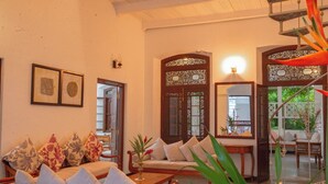 A spacious living area with a high ceiling, a wooden staircase, and a balcony. - Idda Bouqtiue Villa  (Ahangama)