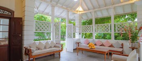 A spacious room with a high ceiling and wooden beams, featuring a wooden bench and a sofa with cushions.