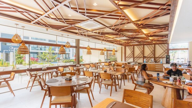 Un restaurant modern amb mobiliari de fusta i il·luminació penjant.