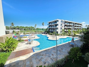 A resort with a large swimming pool, multiple balconies, and lush greenery. - Makia Resort Muro Alto by BLU stay (Ipojuca)