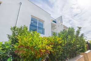 Een modern gebouw met een witte gevel, blauwe luiken en een balkon.