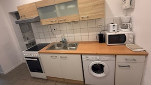 Een praktische keuken met een fornuis, oven, spoelbak, magnetron en vaatwasser.