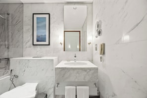 A modern bathroom with a marble sink, a framed picture, and a mirror. - Snug Studio in Dubai Mall Steps From Burj Khalifa (Dubai)