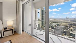 A modern hotel room with a large sliding glass door leading to a balcony with a city view. - Snug Studio in Dubai Mall Steps From Burj Khalifa (Dubai)