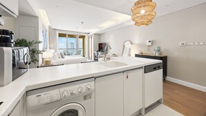 A modern kitchen with a built-in washer and dryer, a large window, and a dining area with a view. - Snug Studio in Dubai Mall Steps From Burj Khalifa (Dubai)