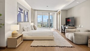 A modern hotel room with a large bed, a TV, a sofa, and a balcony with a city view. - Snug Studio in Dubai Mall Steps From Burj Khalifa (Dubai)