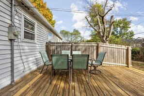 A deck with a table and chairs, a wooden fence, and a house with siding and a window. - Pet-Friendly Broad Ripple Home W/ Fenced Backyard (Indianapolis)