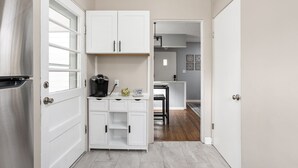 A compact kitchen with white cabinets, a coffee machine, and a refrigerator. - Pet-Friendly Broad Ripple Home W/ Fenced Backyard (Indianapolis)