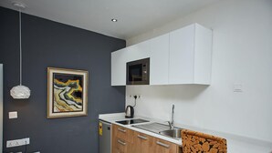 A modern kitchen with white cabinets, a built-in microwave, and a sink. - The Cabin Hotel (Accra)