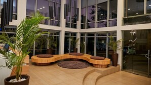 Un'ampia hall con grandi finestre, una zona salotto dalle linee curve e piante in vaso.