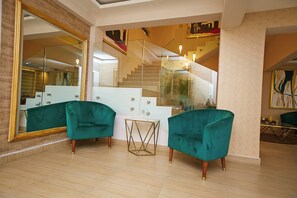 Un intérieur moderne avec des fauteuils turquoise, un escalier en verre et un grand miroir.