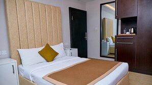 A hotel room with a bed, a nightstand, a wardrobe, and a mirror. - The Cabin Hotel (Accra)