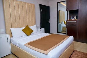 A hotel room with a bed, a nightstand, a wardrobe, and a mirror. - The Cabin Hotel (Accra)