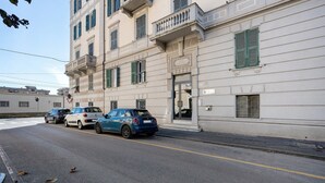 Straatbeeld met geparkeerde auto's en een gebouw met een balkon.
