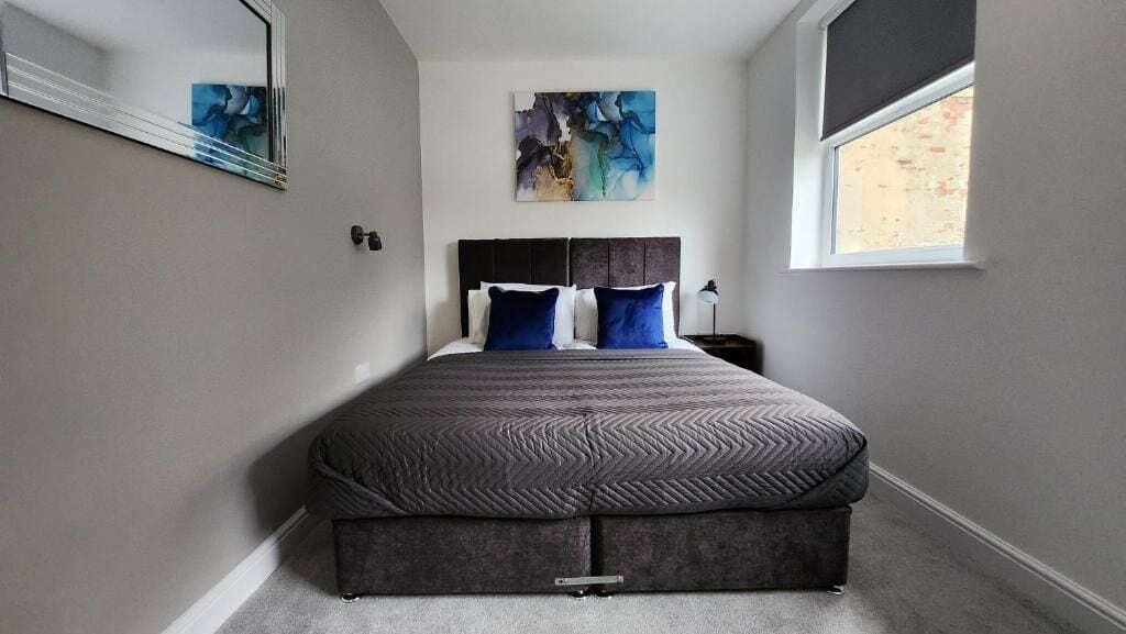 A bedroom with a bed, a window, and a painting on the wall.