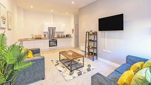 Apartamento moderno com cozinha, sala de estar e televisão de tela plana na parede.