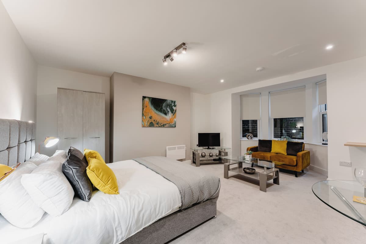 A modern bedroom with a bed, bedside table, and a TV.