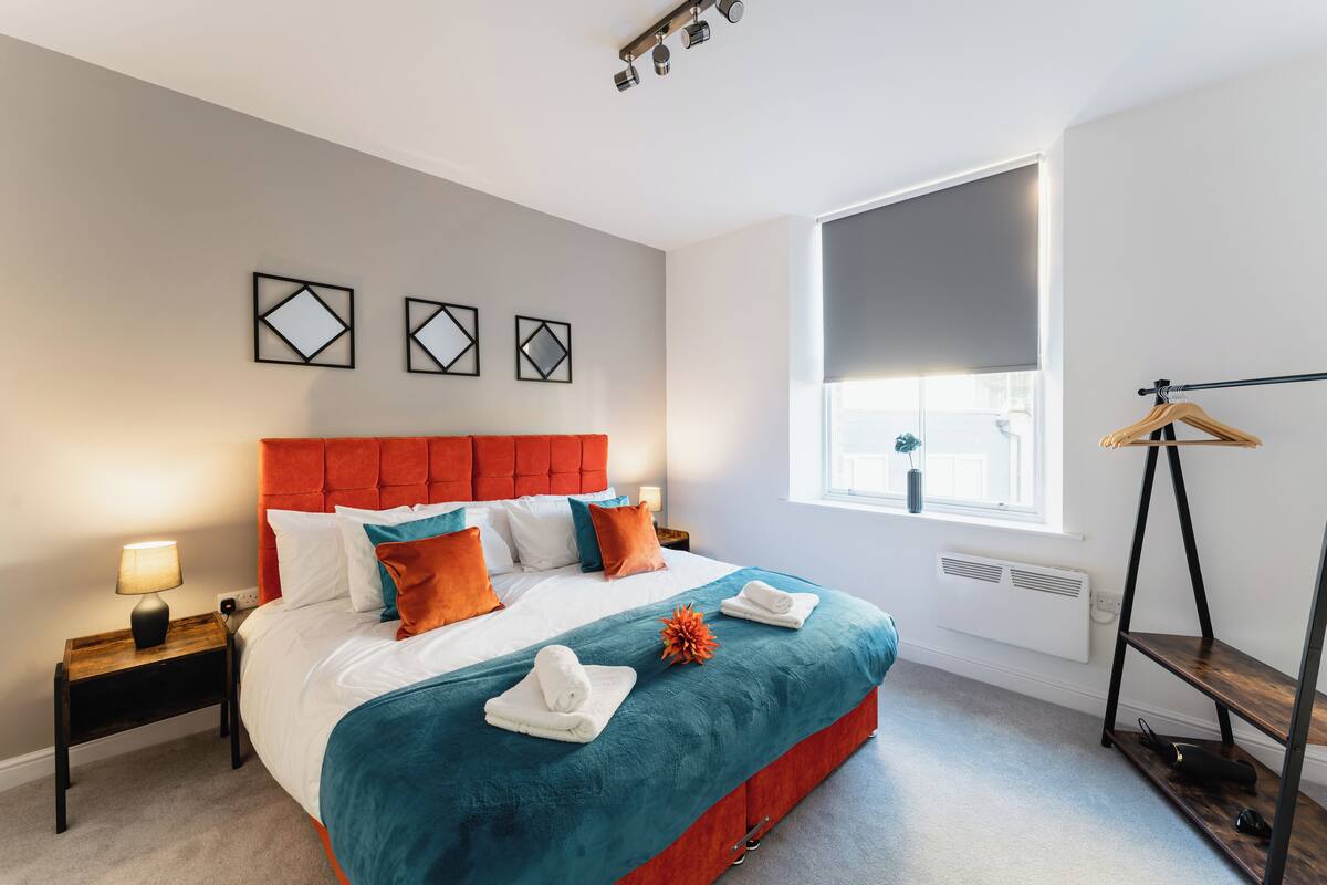 A modern bedroom with a large bed, a red headboard, and a window with a view.