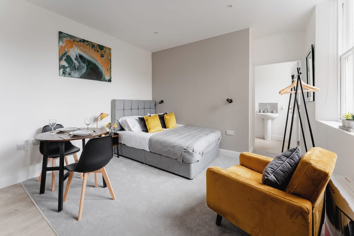 A modern bedroom with a bed, bedside table, and a desk area.