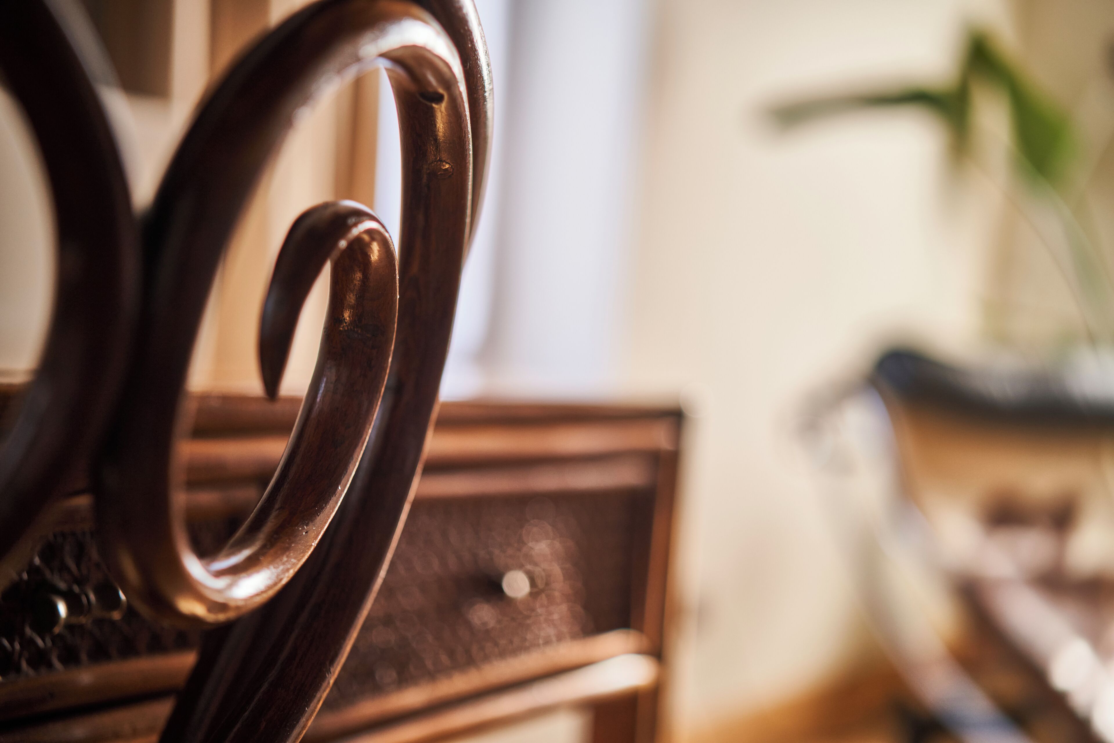 A close-up of a wooden chair with a curved backrest and a textured seat.