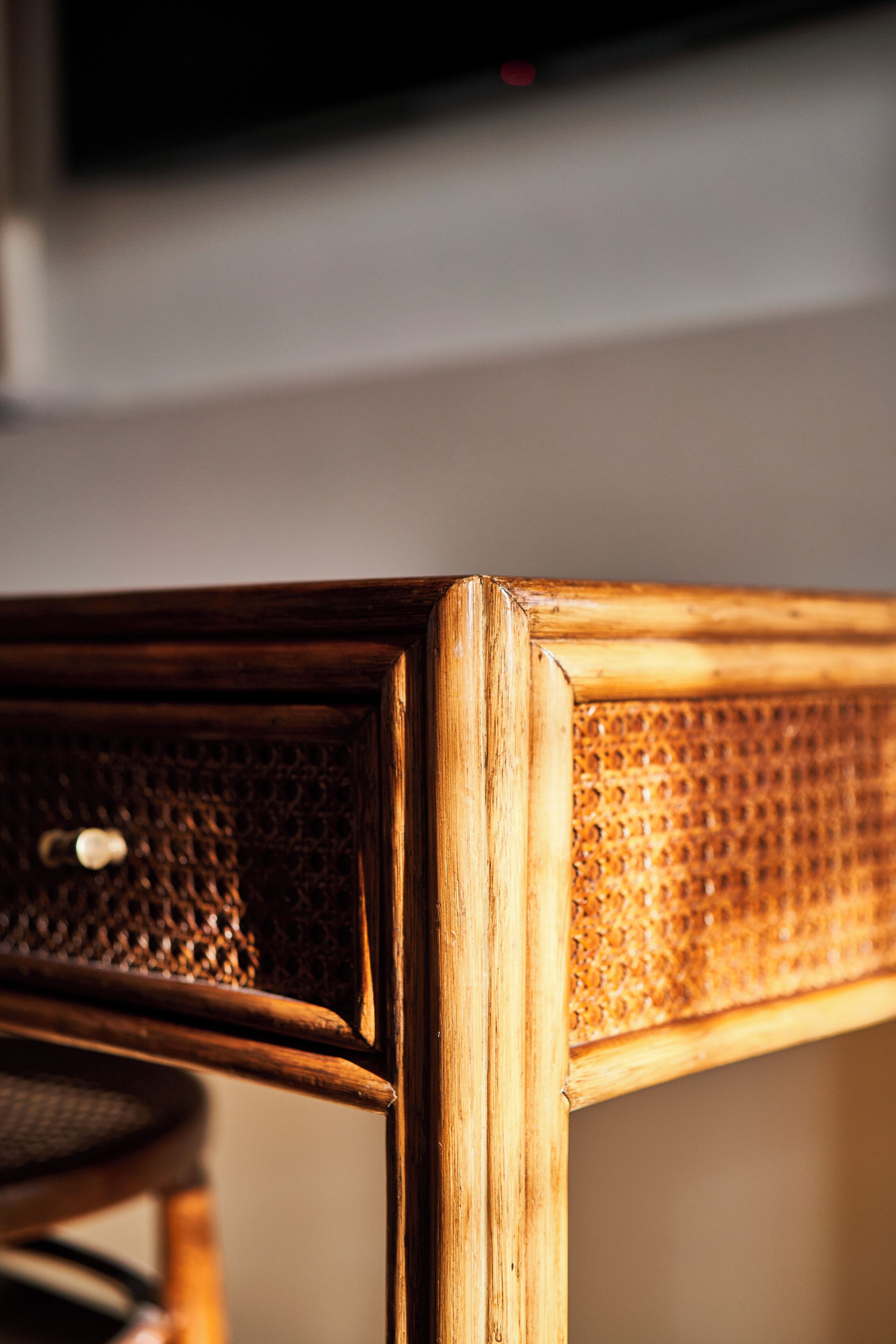 A close-up of a wooden chair with a woven backrest and a metal frame.