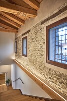 Una escalera de madera con paredes de piedra y una ventana con diseño de cuadrícula.