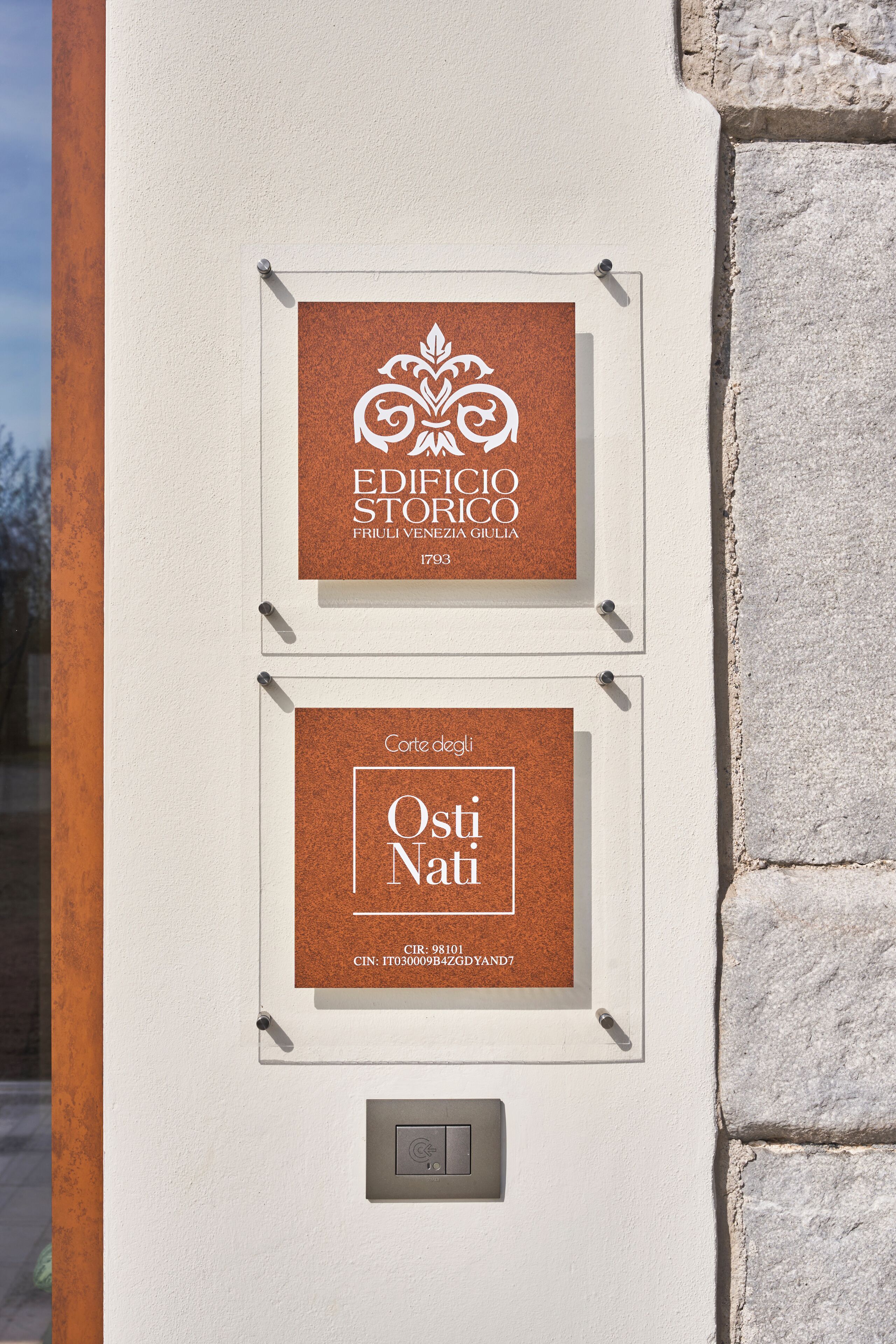 Deux panneaux encadrés sont accrochés au mur, l’un porte l’inscription « EDIFICIO STOFICO » et l’autre « Corte dei Nati ».