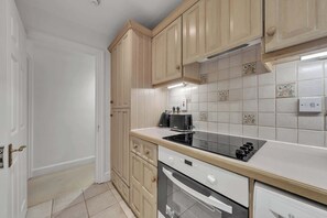 A kitchen with wooden cabinets, a black stove, and a tiled backsplash.