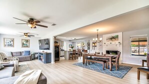 A spacious living room with a large sofa, a dining area with a wooden table, and a kitchen in the background.