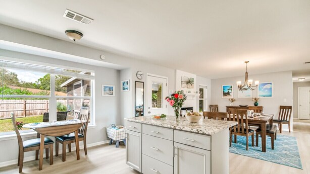 A spacious kitchen with a large island, a dining area with wooden chairs, and a view of the backyard.
