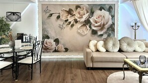 Un salon moderne agrémenté d’une grande fresque florale, un coin repas avec une table en verre et un canapé orné de coussins décoratifs.