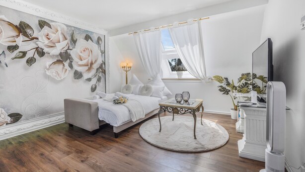 Une chambre moderne avec un grand décor mural floral, un lit confortable, une table de chevet avec des lampes et un téléviseur.