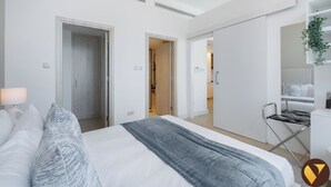 Un dormitorio moderno con una cama grande, una mesita de noche, una lámpara colgante y un armario.