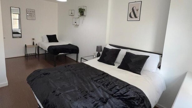 Un dormitorio moderno con una cama grande, una mesita de noche, una silla y una lámpara colgante.