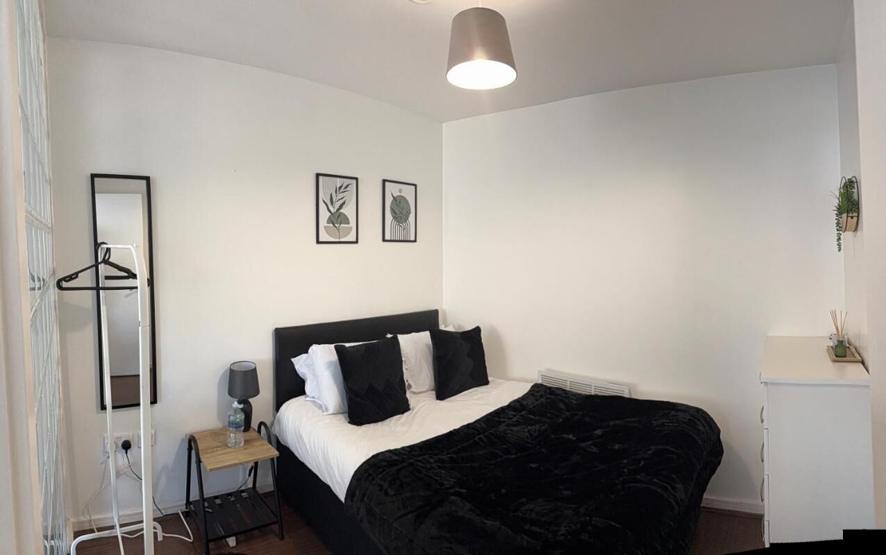 Una camera da letto con un letto, un comodino, una lampada e un'opera d'arte appesa al muro.