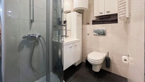 Ein modernes Badezimmer mit einer Glaskabine zur Dusche, einer Toilette, einem Waschbecken und einem Handtuchwärmer.