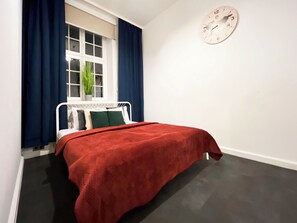 A bedroom with a bed, a clock on the wall, and a window with curtains. - AS HOME Rynek 24 (Wrocław)