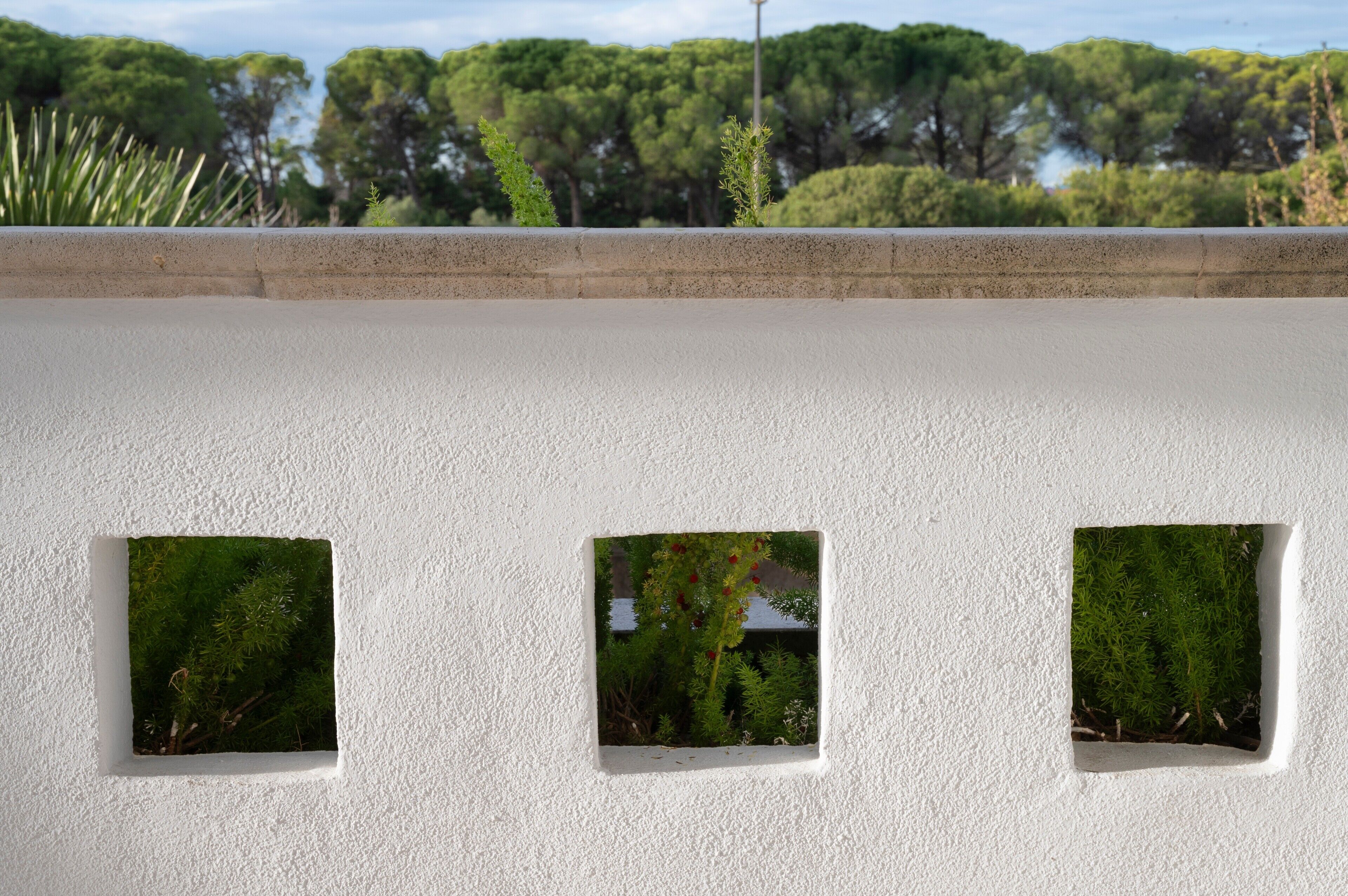 A white wall with three square windows.