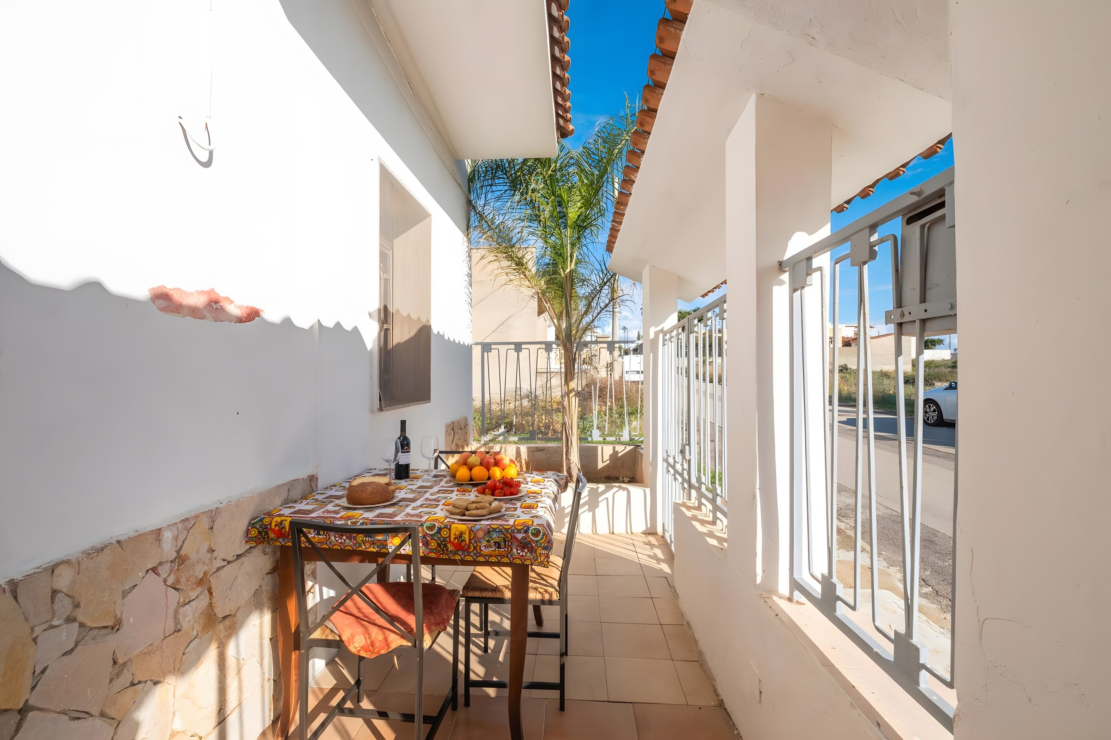 Ein schmaler Balkon im Freien mit einem Tisch für zwei Personen, einer Flasche und einer Schale Obst.