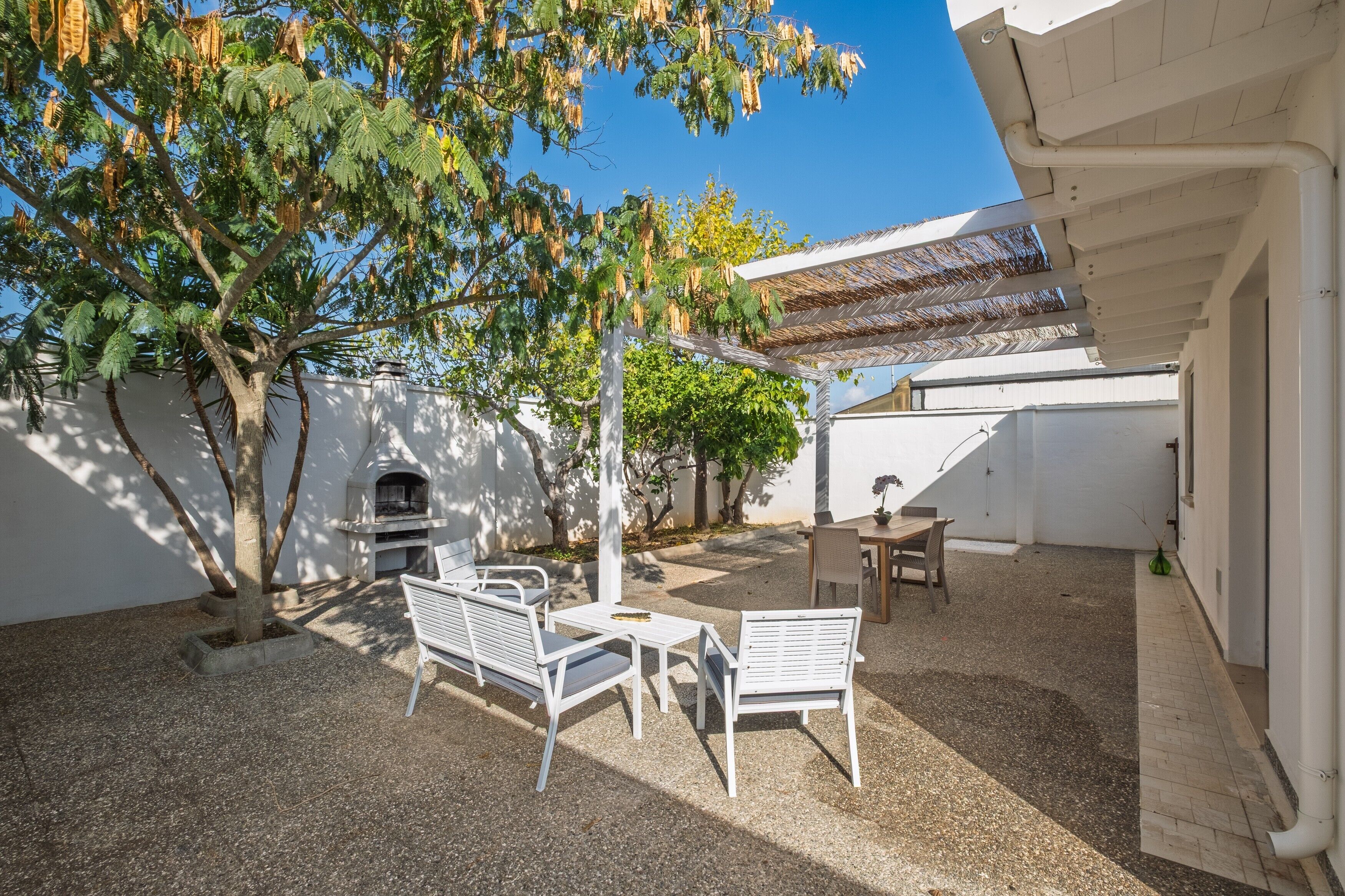 Eine Außenpatio mit Grill, Sitzgelegenheit und einer Pergola.