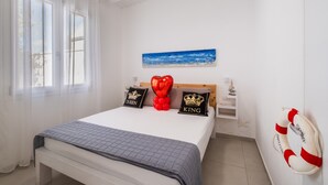 Une chambre à coucher avec un lit, un tableau, une décoration en forme de cœur faite de ballons et un anneau de sauvetage accroché au mur.