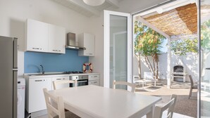 Une cuisine moderne avec des meubles blancs, un pare-feu bleu et un coin repas comprenant une table et des chaises blanches.
