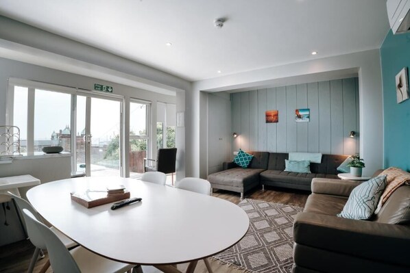 Un salon moderne avec une table blanche, un canapé marron et un tapis à motifs.