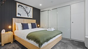 A modern bedroom with a wooden bed, a green throw blanket, and a large wardrobe.