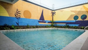 Une piscine ornée d’une fresque représentant un voilier, des palmiers et un coucher de soleil.