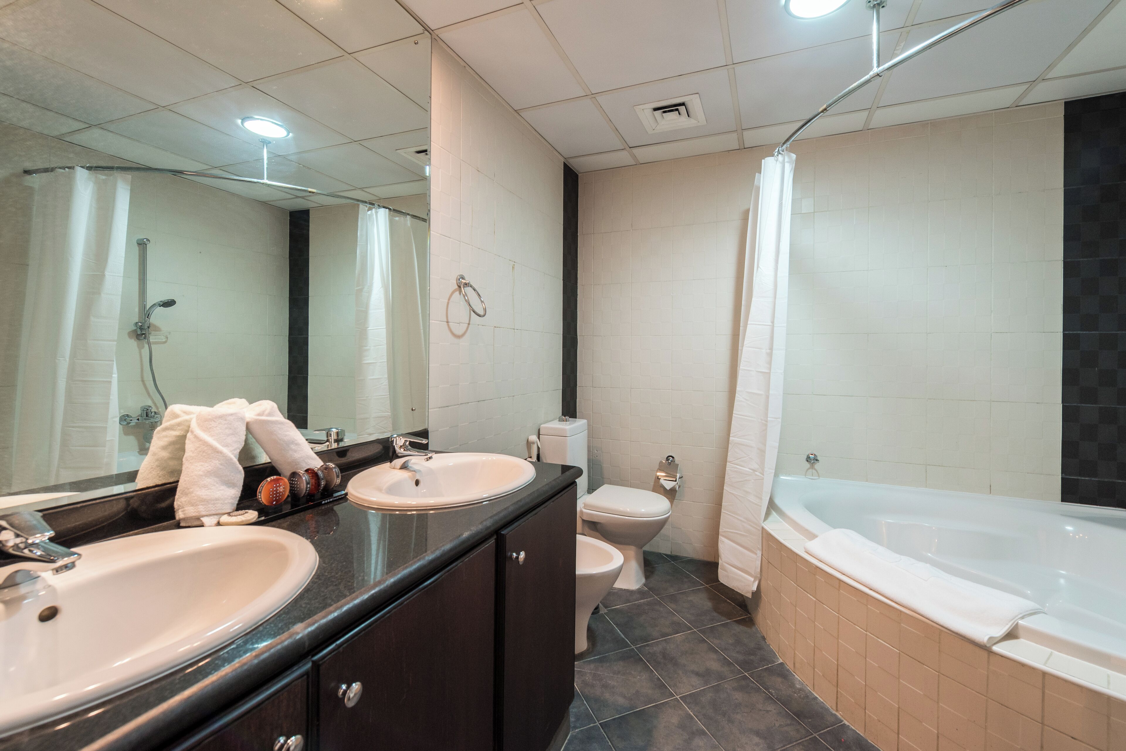 Un baño moderno con lavamanos doble, inodoro, bañera y zona de ducha.