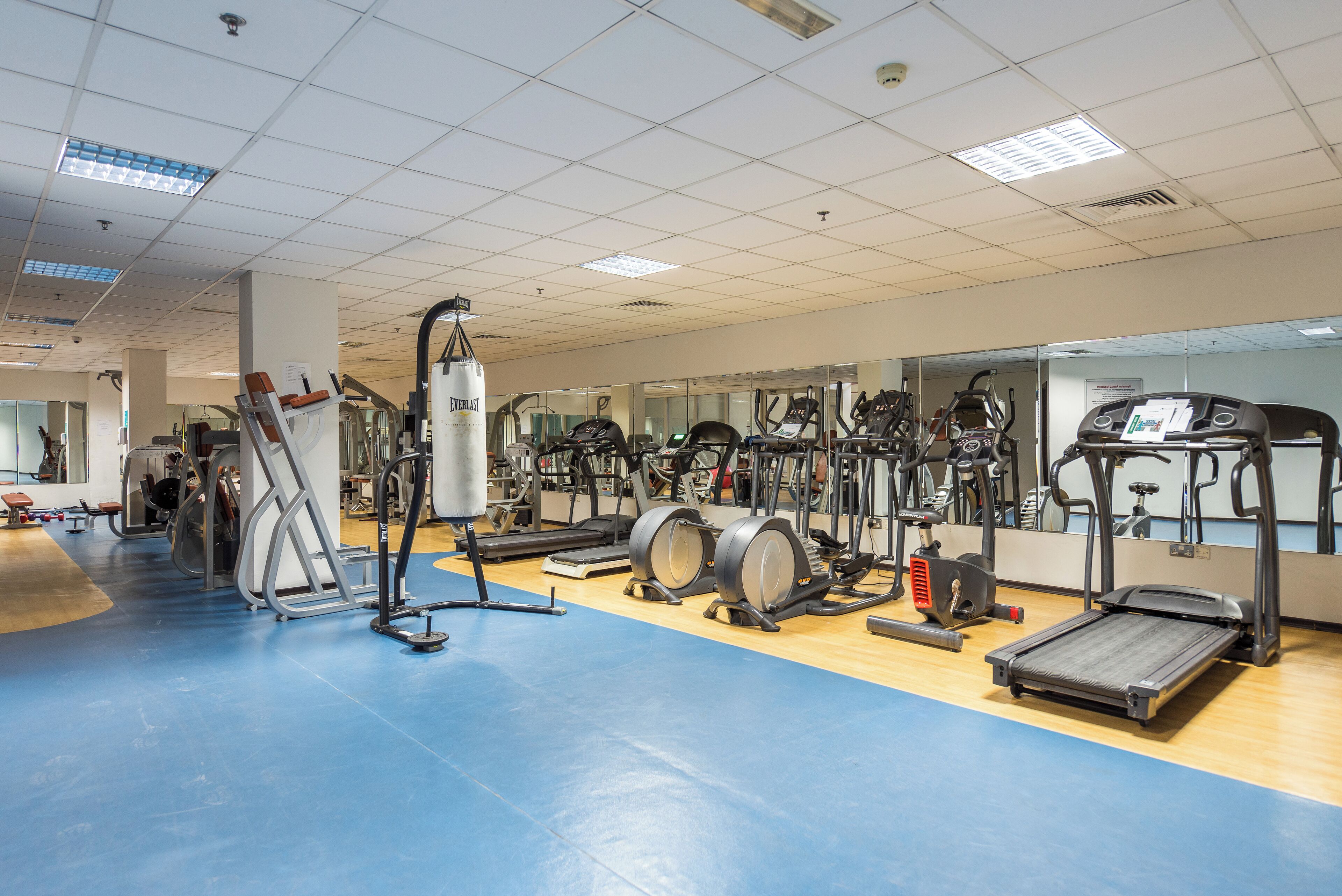 A gym with various exercise equipment, including treadmills, elliptical machines, and weight machines.