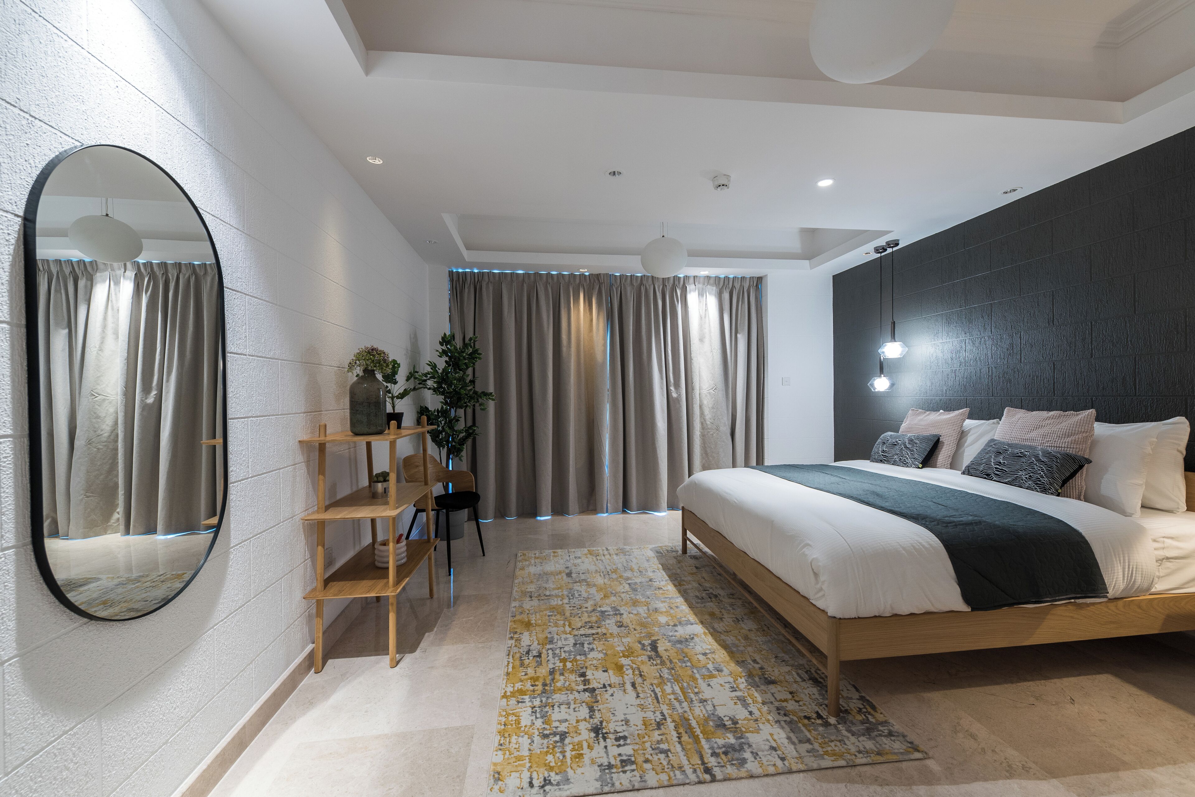 Une chambre moderne avec un grand lit, un miroir rond et une étagère en bois.